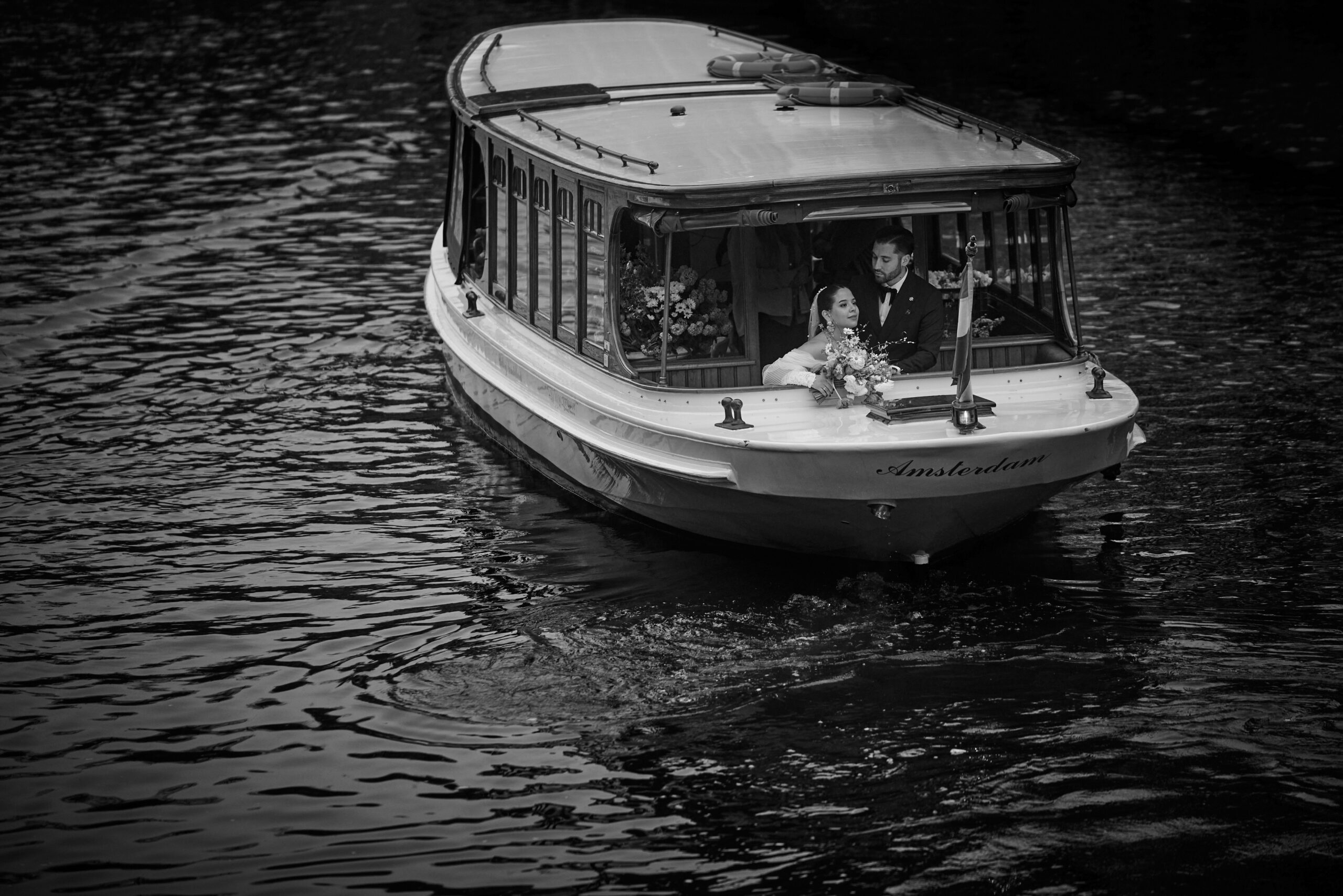 A wedding couple in a boat driving the canals of Amsterdam on their wedding day